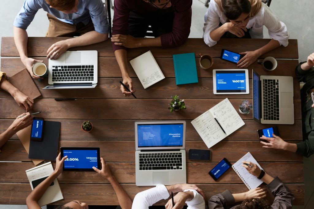 A team collaborating around a table with laptops and tablets